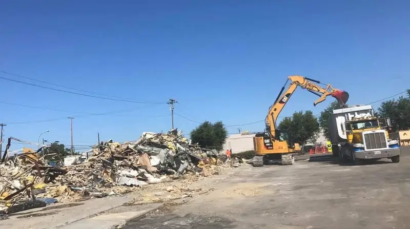 Excavator loading fire and demolition debris onto a haul truck